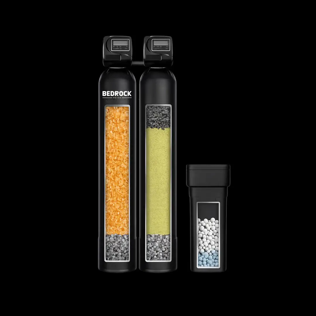 Two tall black tanks side by side, one holding amber resin and one holding pale filter media, with a smaller third tank to the right.