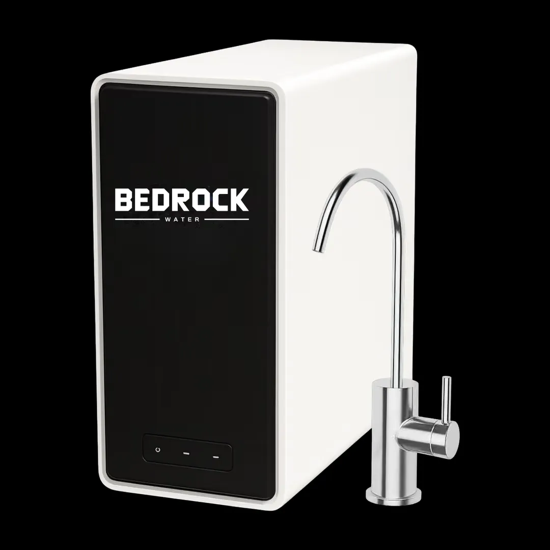 A slim white and black under-sink unit standing next to a chrome drinking-water faucet.